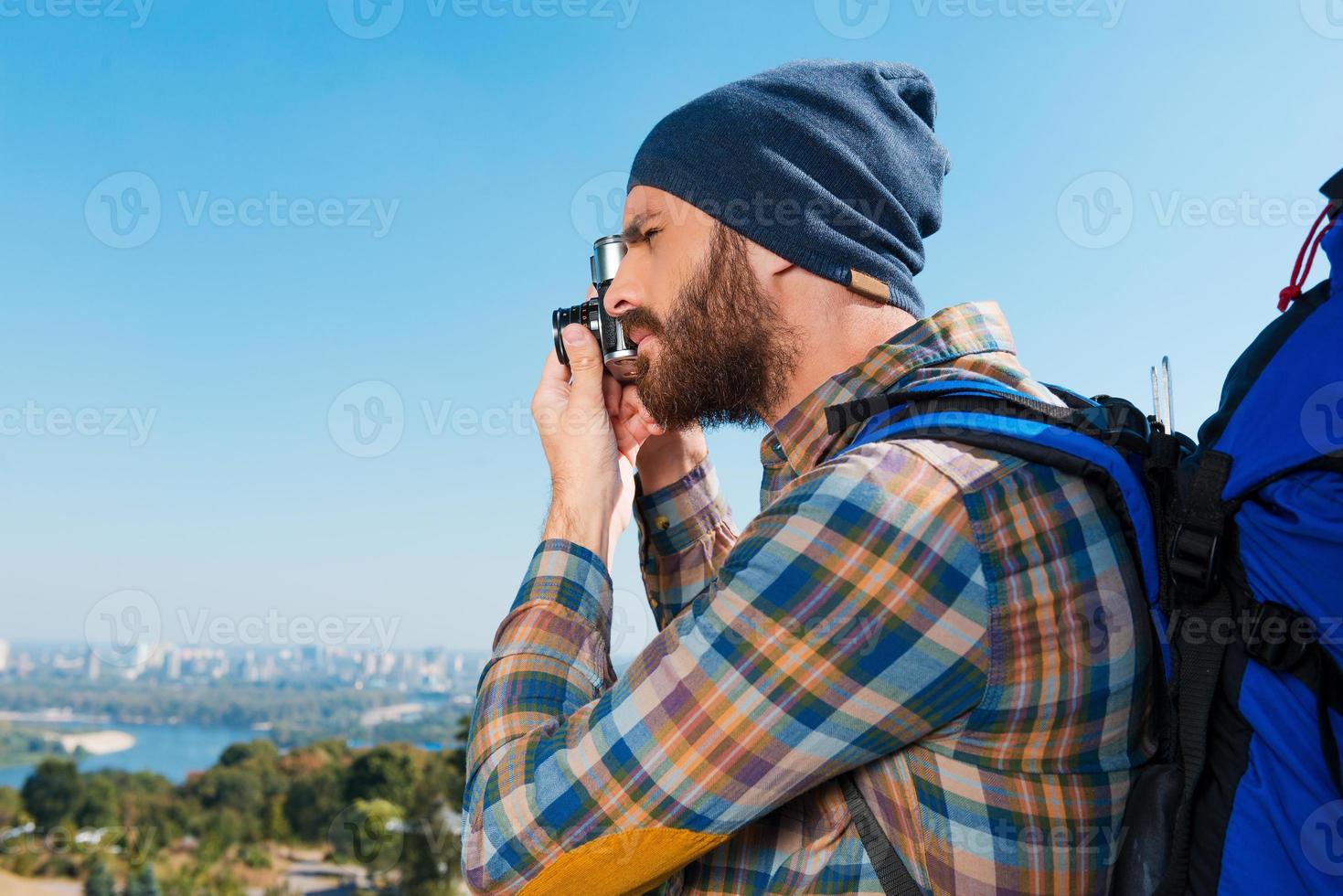 Capturing memories. Handsome young man carrying backpack and taking photo of a view