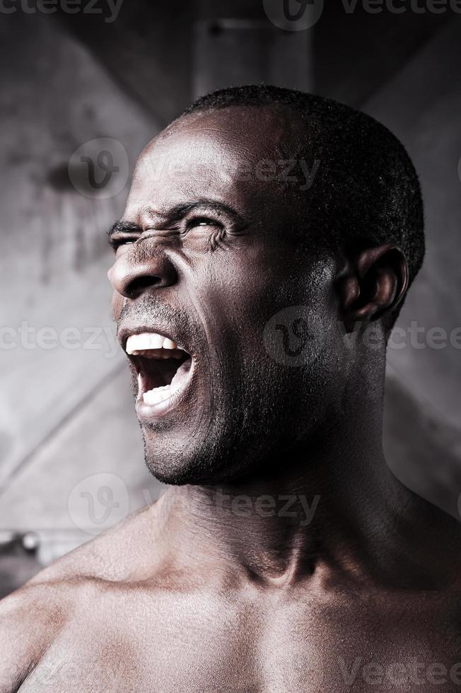 Furious man. Portrait of furious young shirtless African man shouting and looking away photo