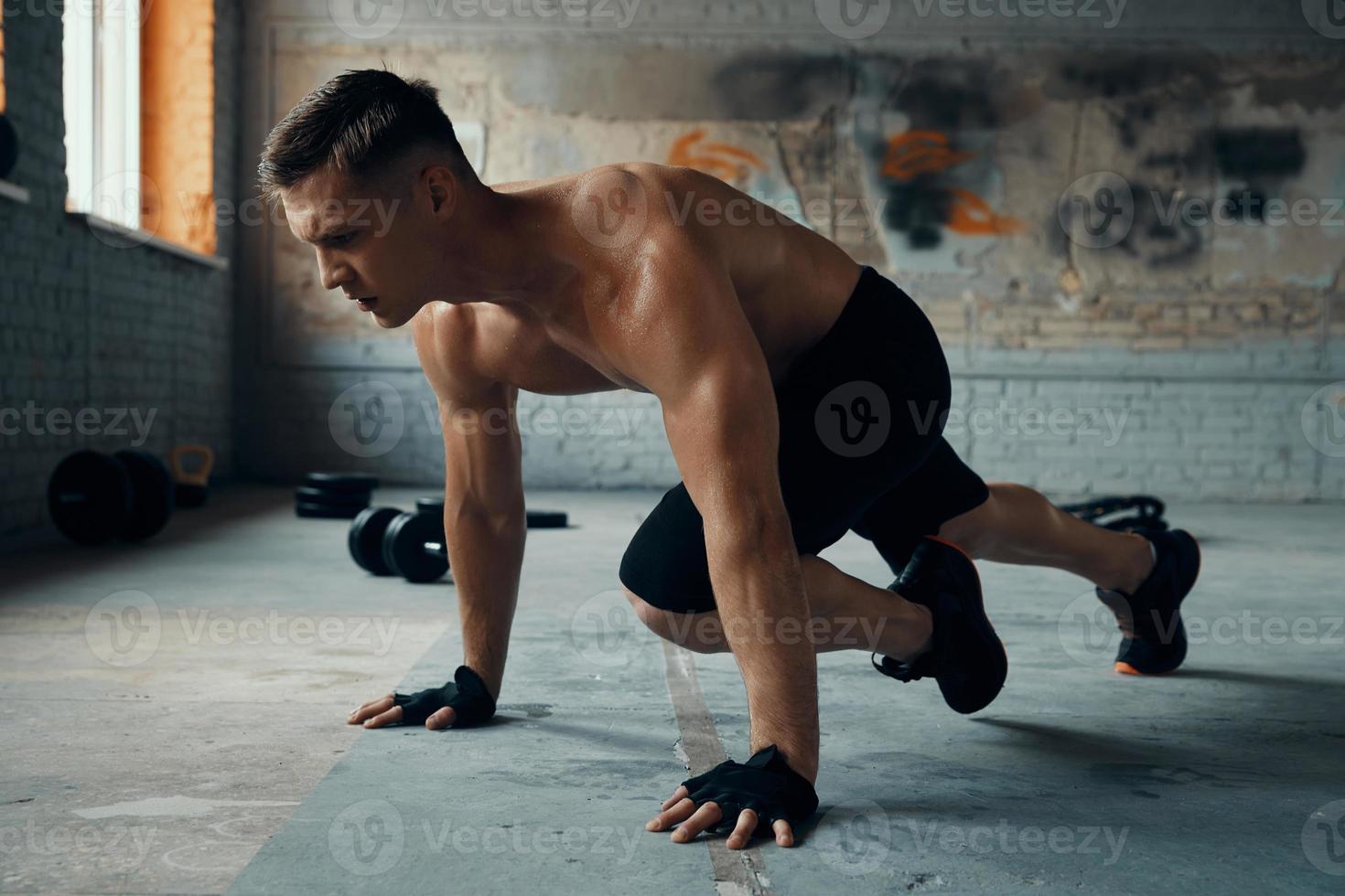 un joven confiado que parece concentrado mientras hace ejercicio en el gimnasio foto