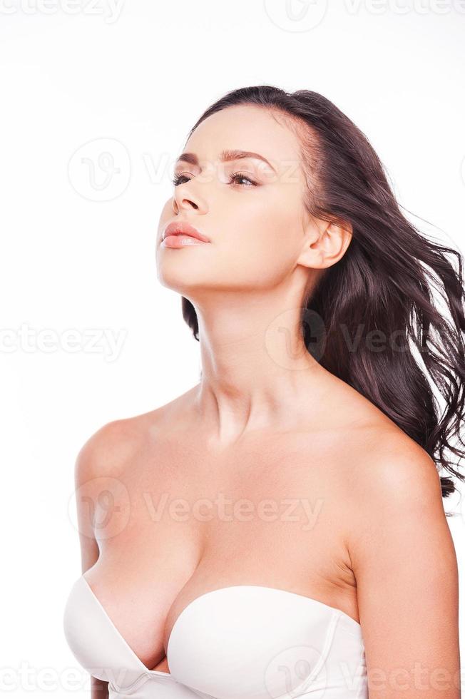 Pure elegance. Beautiful young woman looking away while standing against white background photo