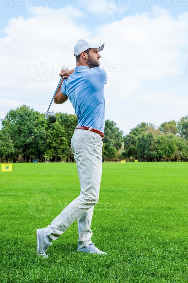 Great strike. Full length of confident golfer swinging his driver and looking away while standing on golf course photo