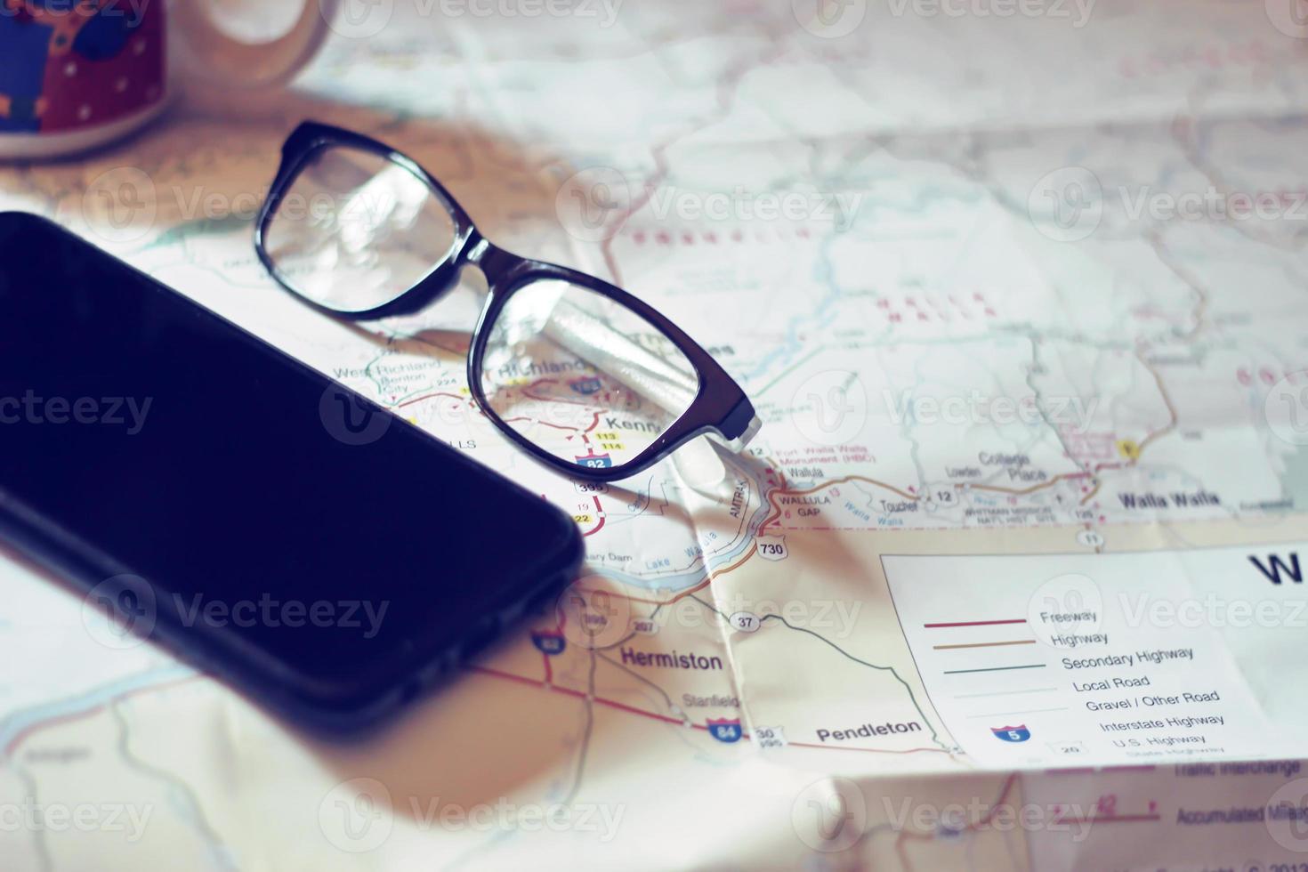 Map, map of Washington state, pen, glasses, cell phone, coffee cup on the table. photo