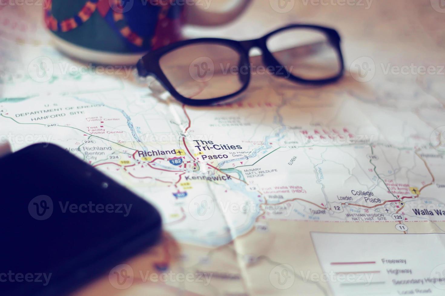 Map, map of Washington state, pen, glasses, cell phone, coffee cup on the table. photo