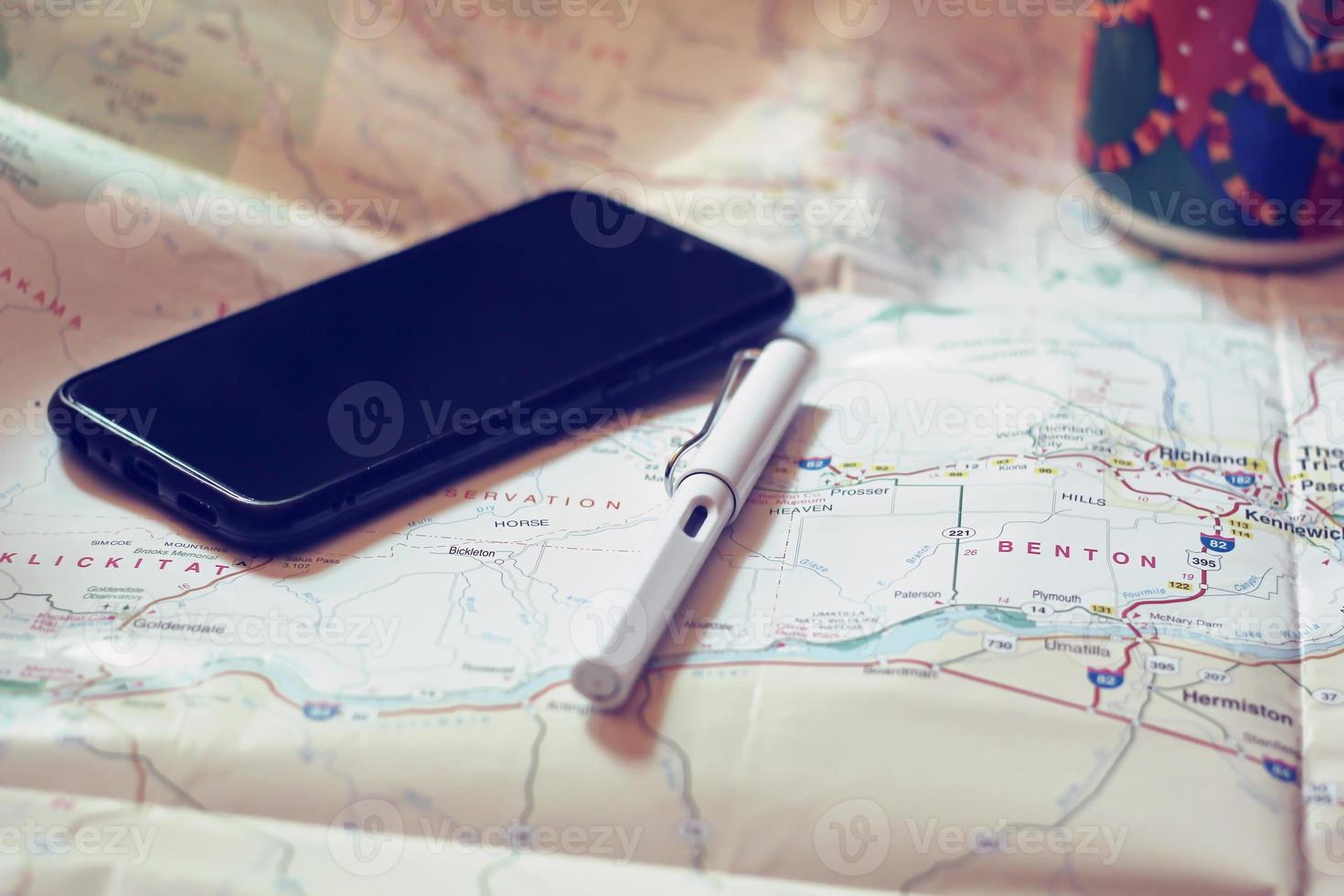 Map, map of Washington state, pen, glasses, cell phone, coffee cup on the table. photo