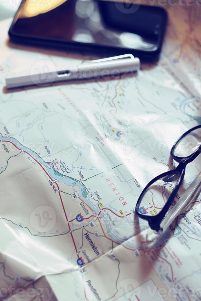 Map, map of Washington state, pen, glasses, cell phone, coffee cup on the table. photo