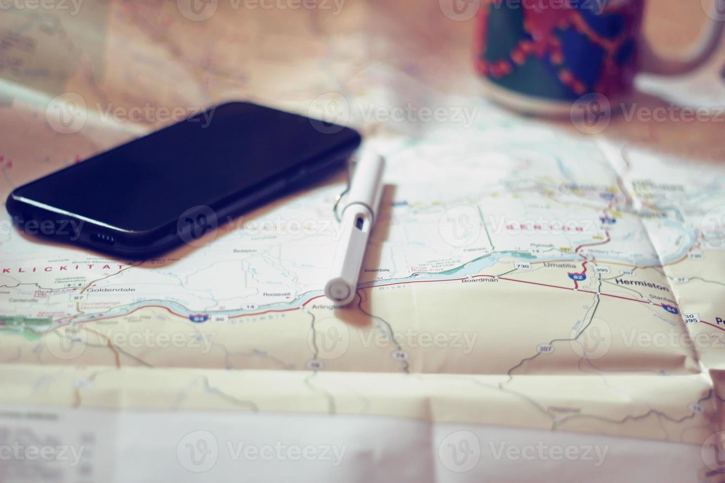 Map, map of Washington state, pen, glasses, cell phone, coffee cup on the table. photo