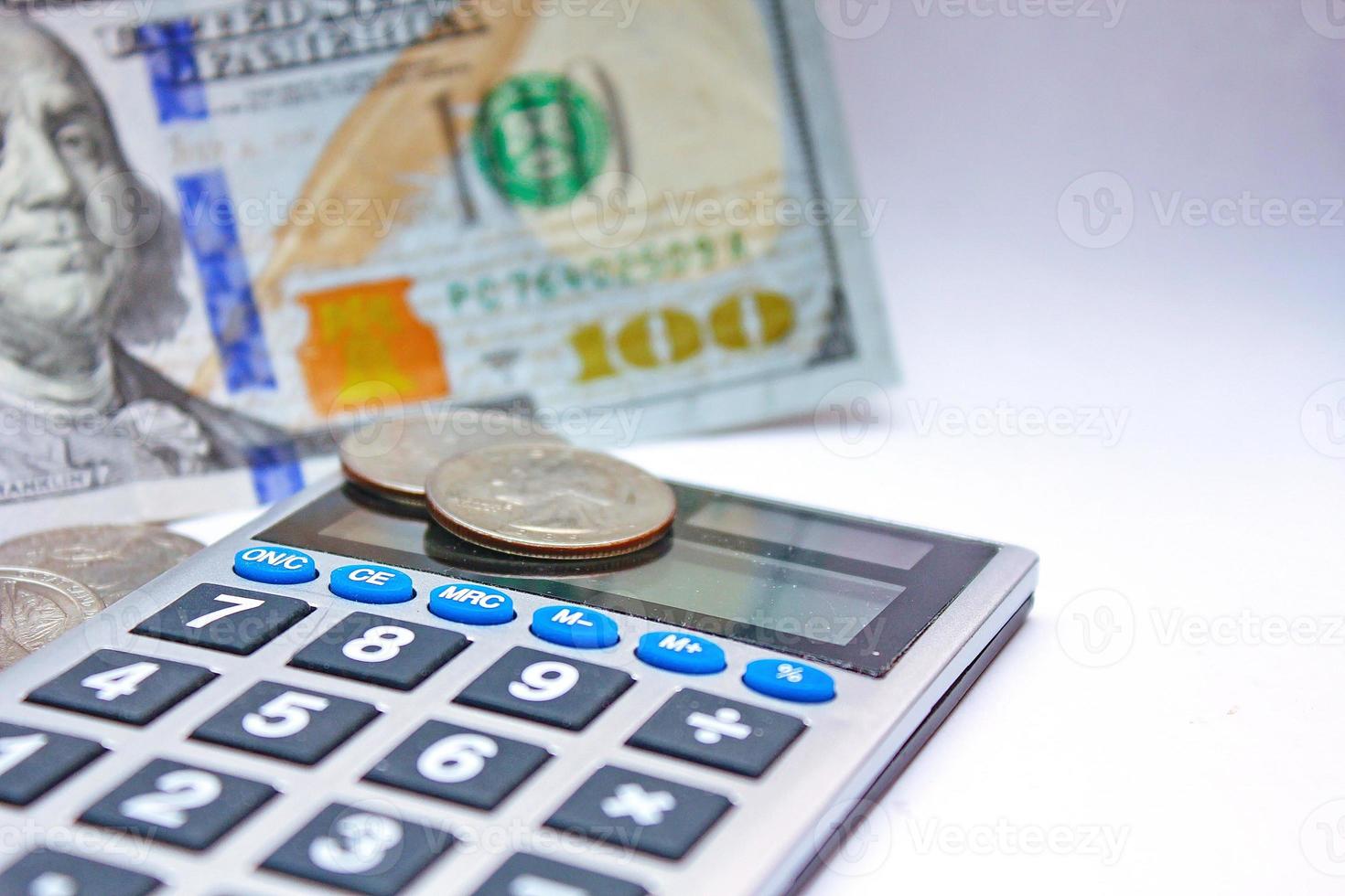 Calculator and dollar bills are placed on a white table. photo