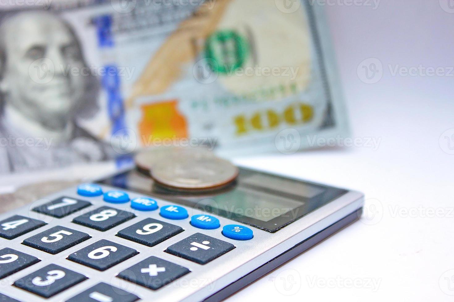 Calculator and dollar bills are placed on a white table. photo