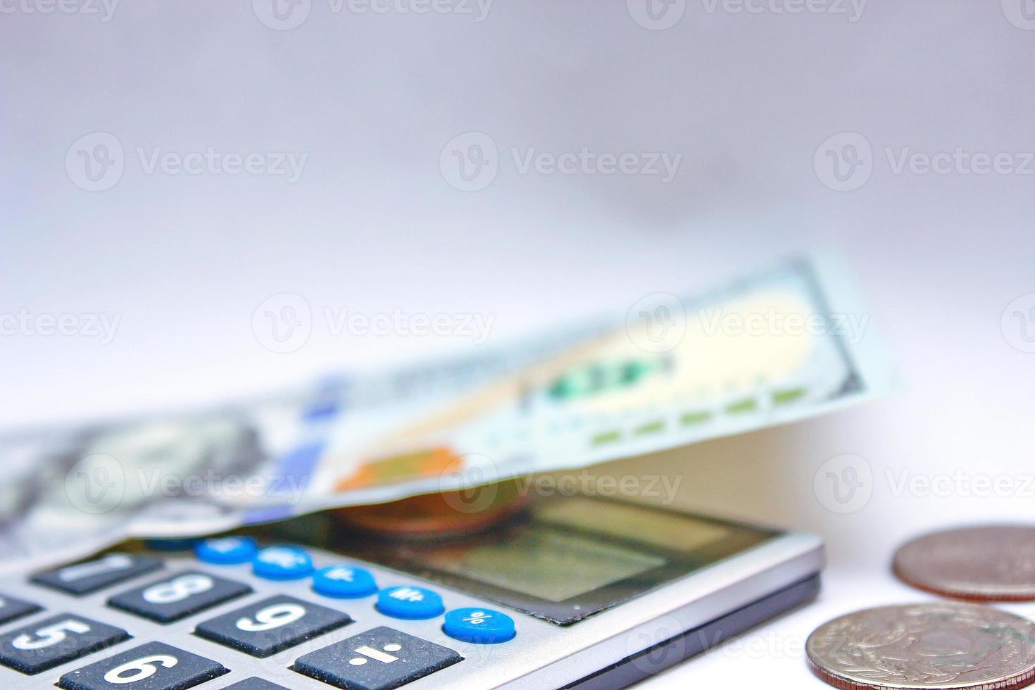 Calculator and dollar bills are placed on a white table. photo