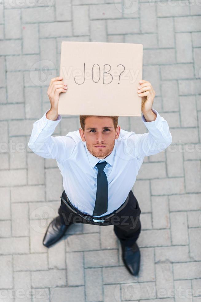 Got job Top view of handsome young man in shirt and tie showing poster with job text message while standing outdoors photo