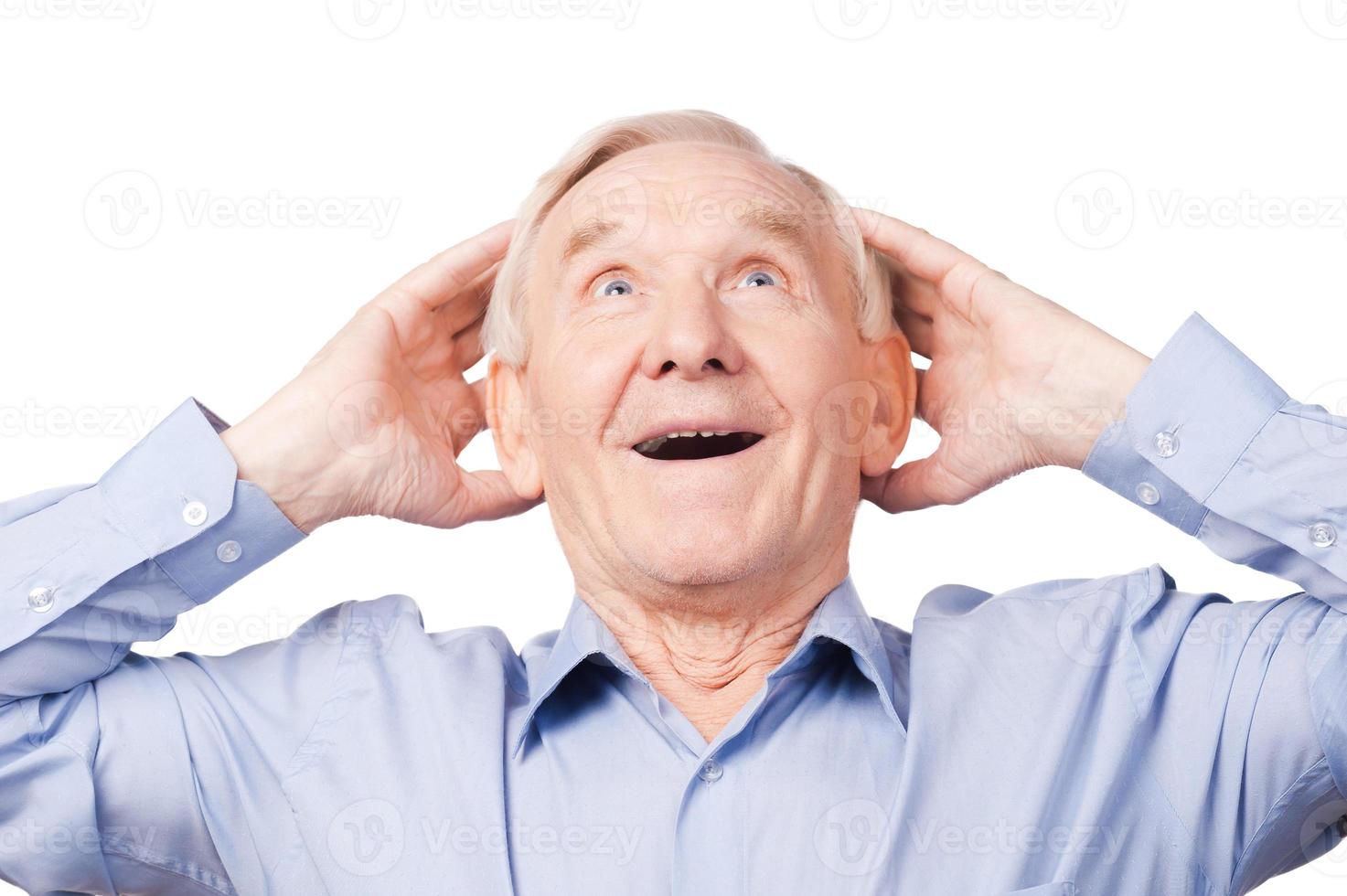 Surprising news. Excited senior man holding hands on his hand and looking away while standing against white background photo