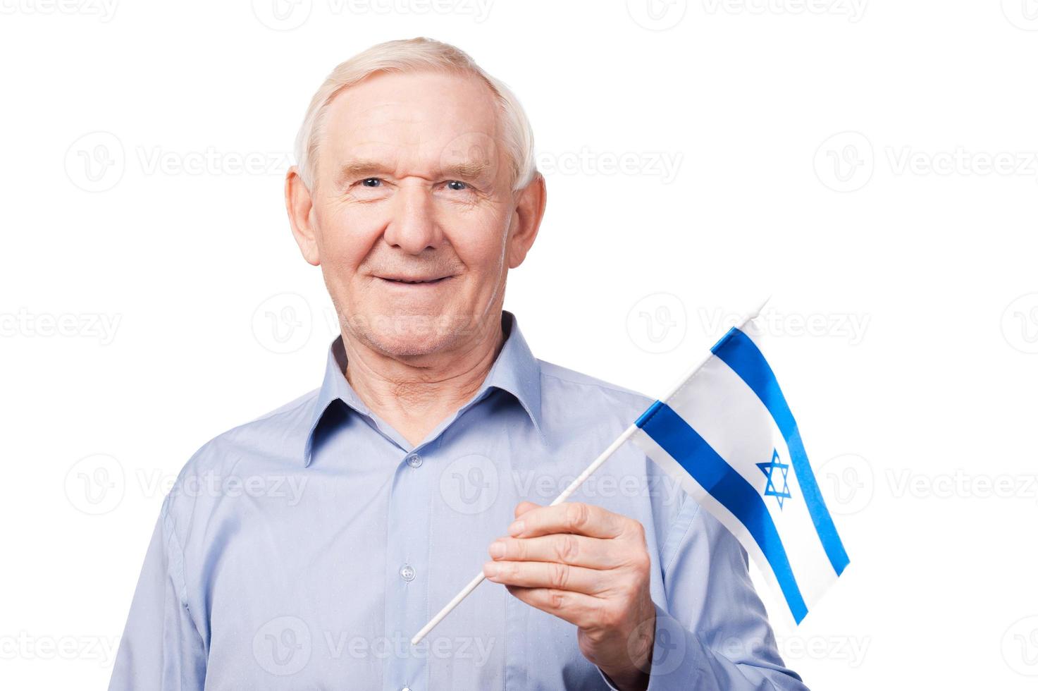 Senior man with Israeli flag. Cheerful senior man holding flag of Israel and smiling at camera while standing against white background photo