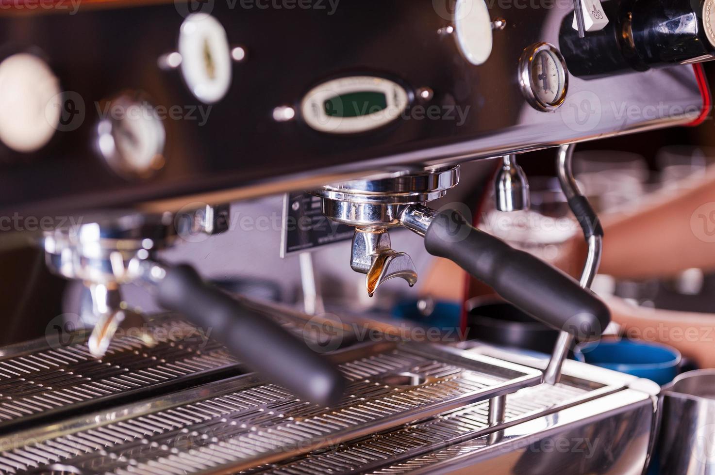 cafetera. imagen de primer plano de una máquina de espresso de metal con alguien trabajando en segundo plano foto