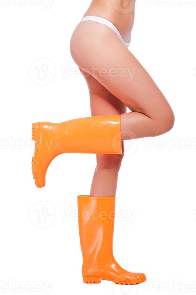 Close-up of young woman wearing gumboots while standing against white background photo