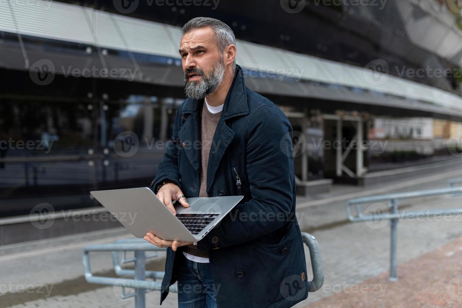 ingeniero de software adulto con una computadora portátil en las manos en el contexto de un centro de negocios de oficina foto