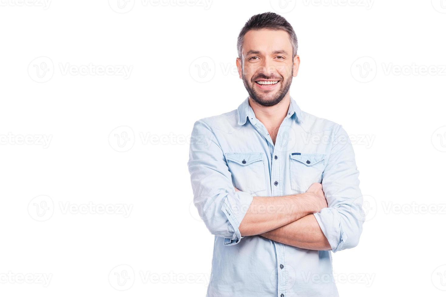 Charming handsome. Handsome young man in casual wear keeping arms crossed and smiling while standing isolated on white background photo