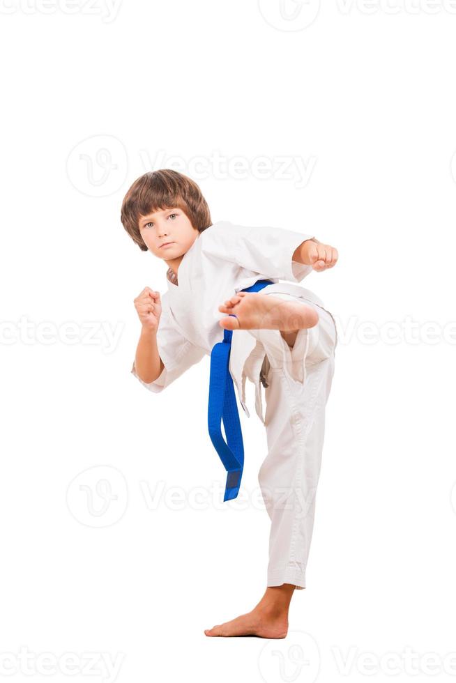 Karate kid. Little boy doing martial arts moves while isolated on white background photo