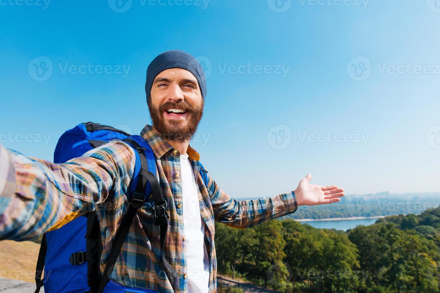 solo mira, estoy aquí, un joven apuesto que lleva una mochila y se toma una foto y señala la vista