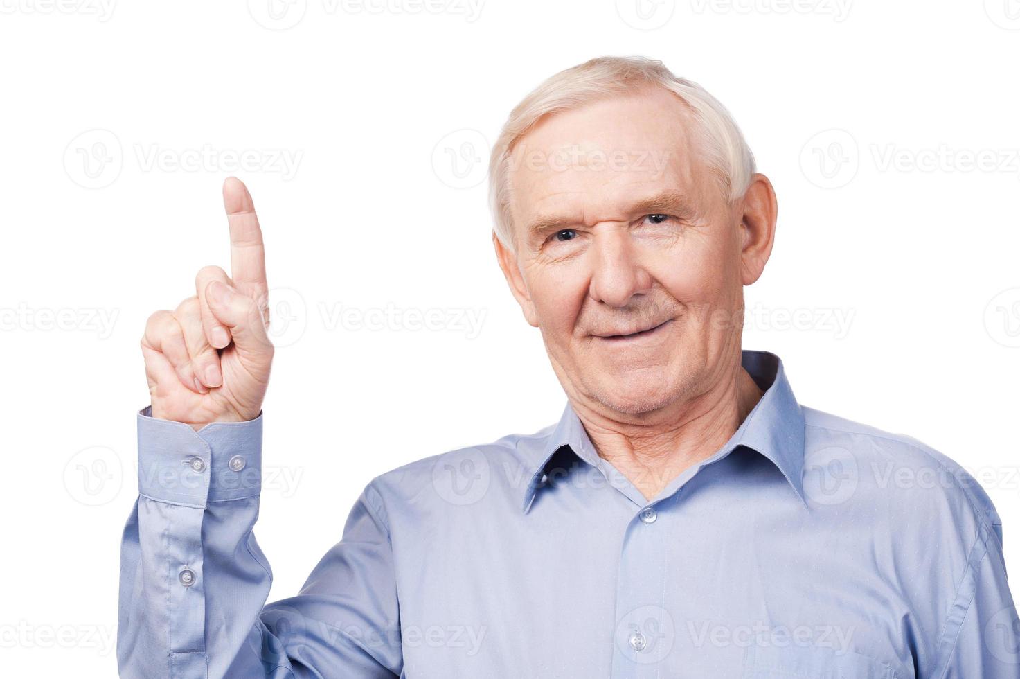 mire allí a un anciano alegre que señala hacia arriba y sonríe mientras se enfrenta a un fondo blanco foto