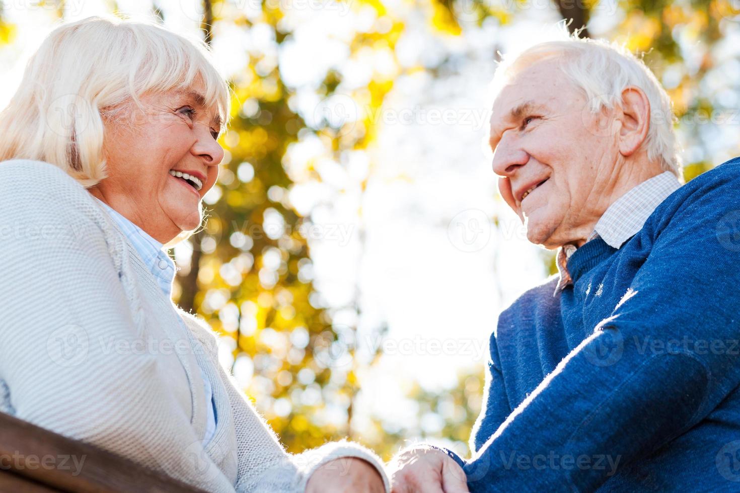 Spending great time together. Low angle view of happy senior couple looking at each other and smiling while standing outdoors photo