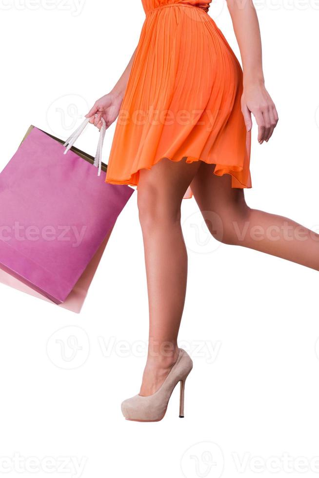 Shopping Close-up of young woman carrying shopping bags and walking while being isolated on white background photo