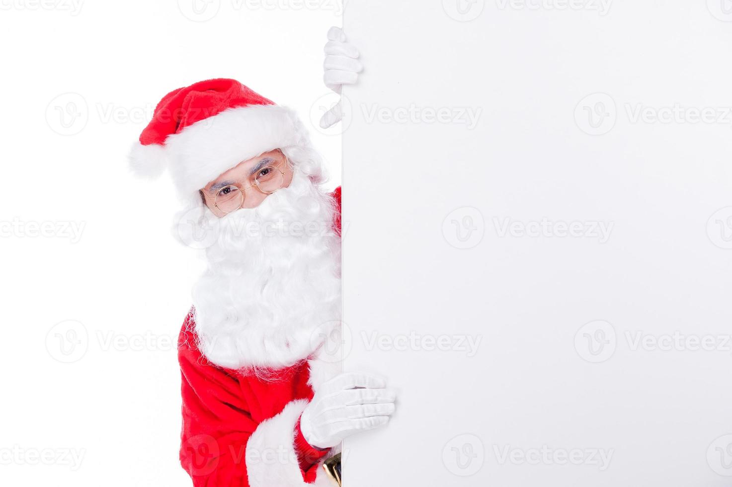 Hi there Traditional Santa Claus looking out of the copy space while being isolated on white photo