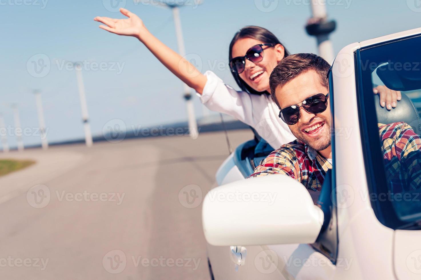 Fun ride. Happy young couple enjoying road trip in their white convertible photo