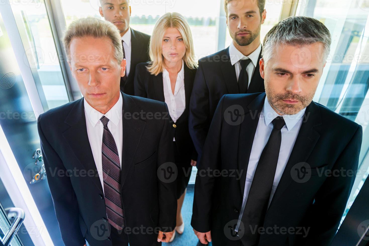 People in elevator. Top view of business people in formalwear standing in elevator photo