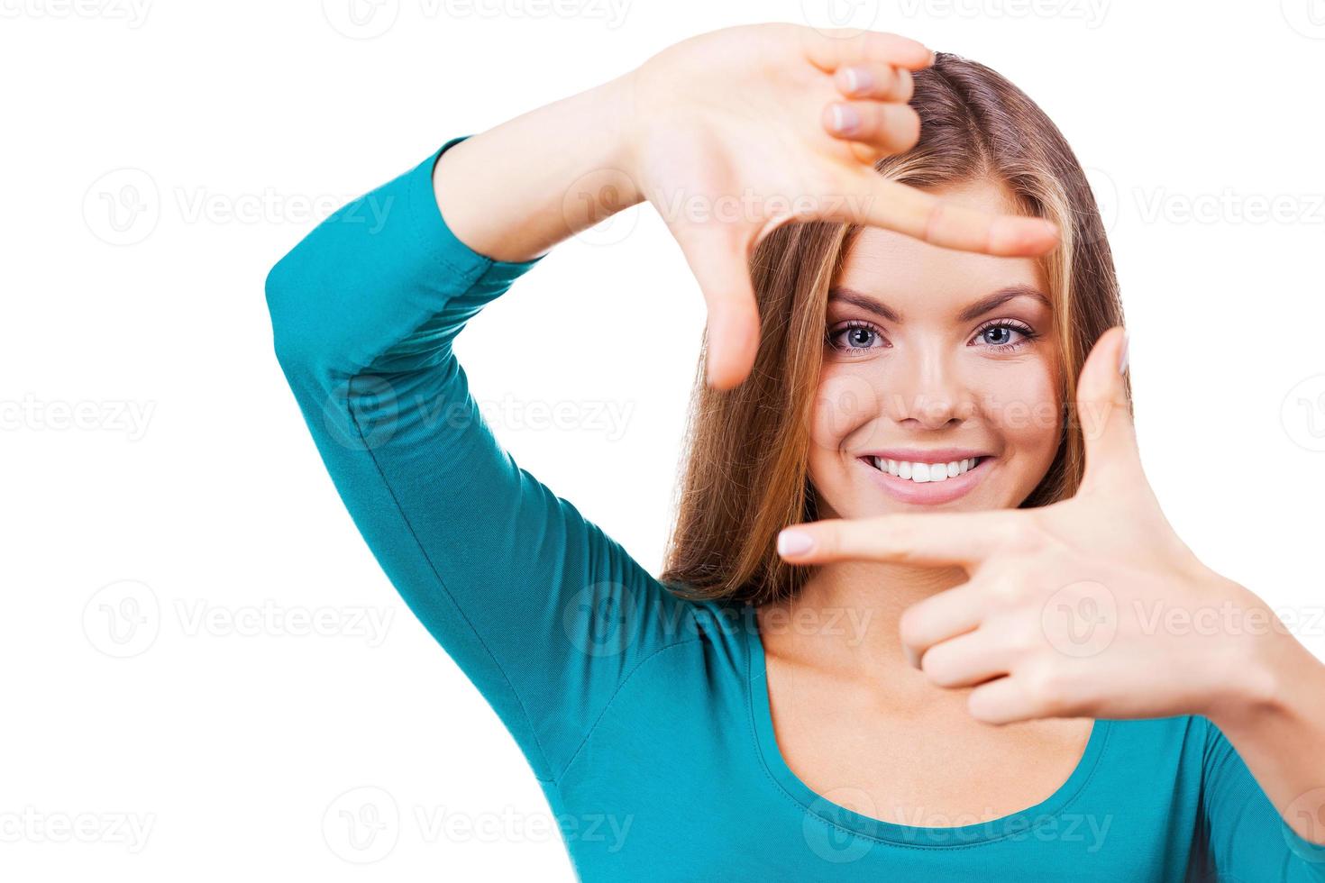 Gesturing finger frame. Beautiful young woman looking at camera and gesturing finger frame while standing isolated on white photo