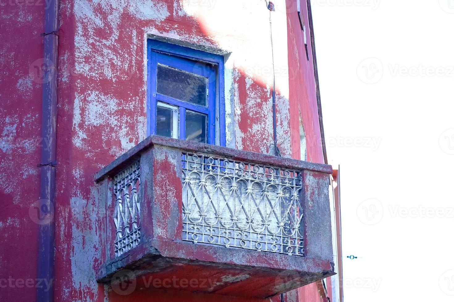 Red old building corner with balcony with blue frame door photo
