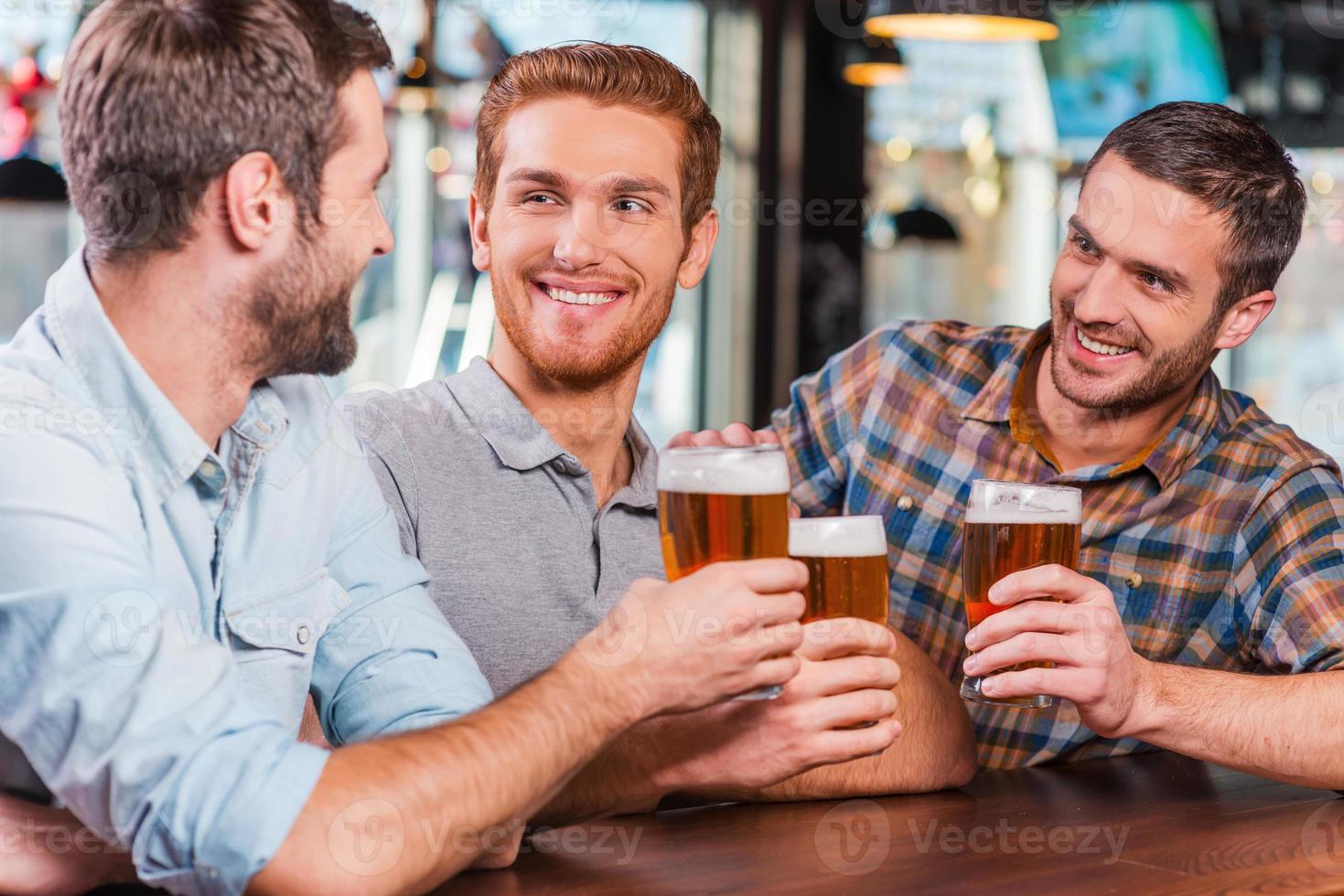 Relaxing after work. Three happy young men in casual wear talking and