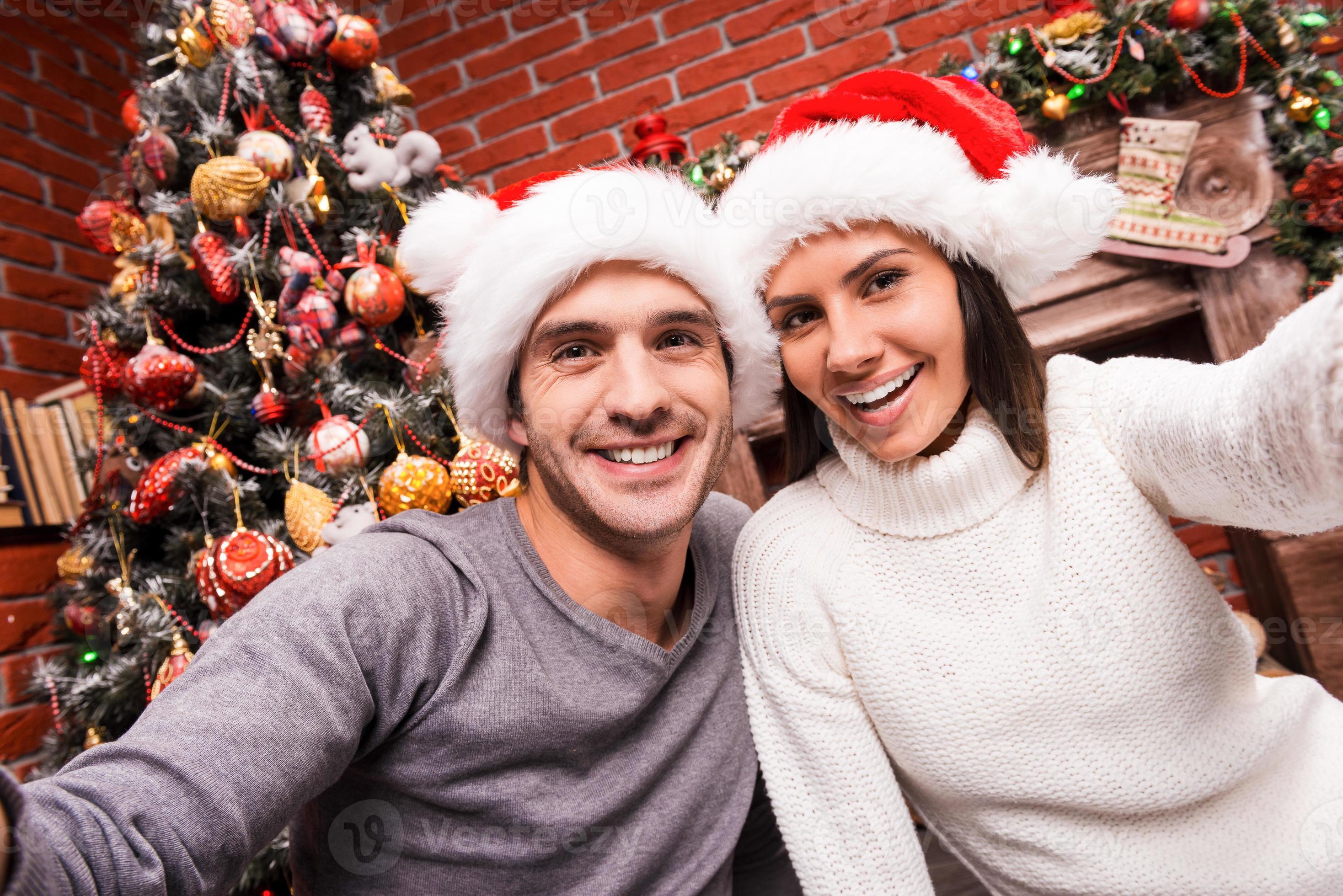 Capturing a happy moment. Beautiful young loving couple bonding to each  other and smiling while making selfie with Christmas Tree in the background  13292958 Stock Photo at Vecteezy