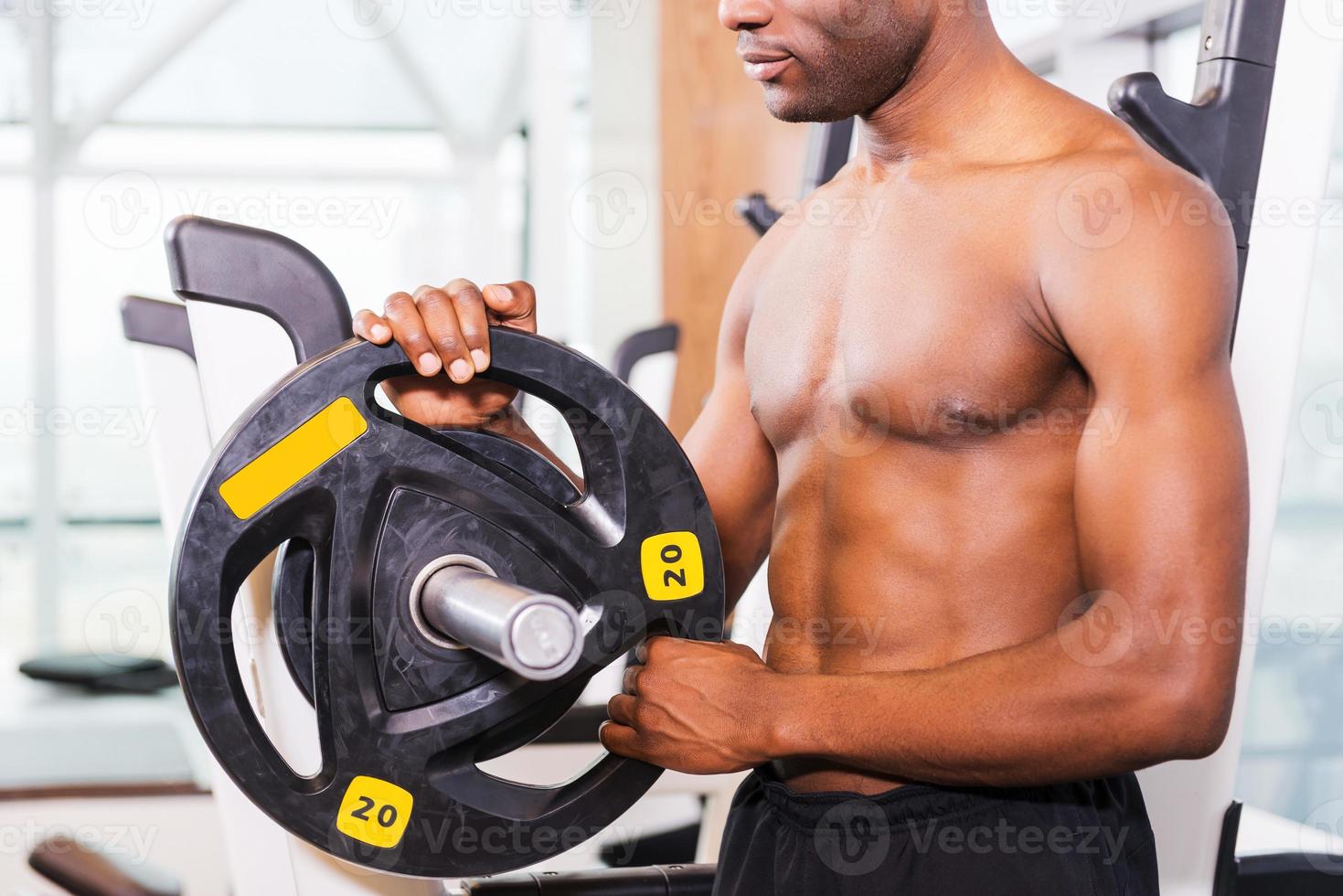 Preparing to training. Close-up of muscular African man preparing to weightlifting while standing in gym photo