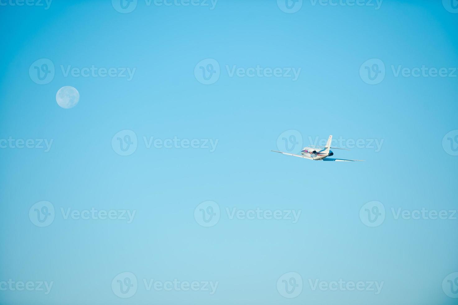 Flying to the moon. Low angle view of airplane flying in the direction of moon photo