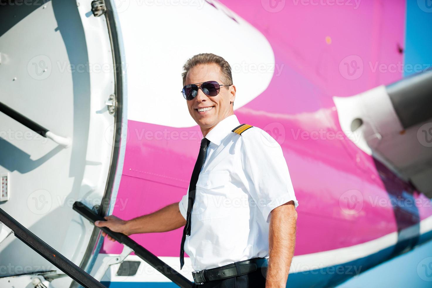 I am ready to flight Confident male pilot in uniform going into the airplane and smiling photo