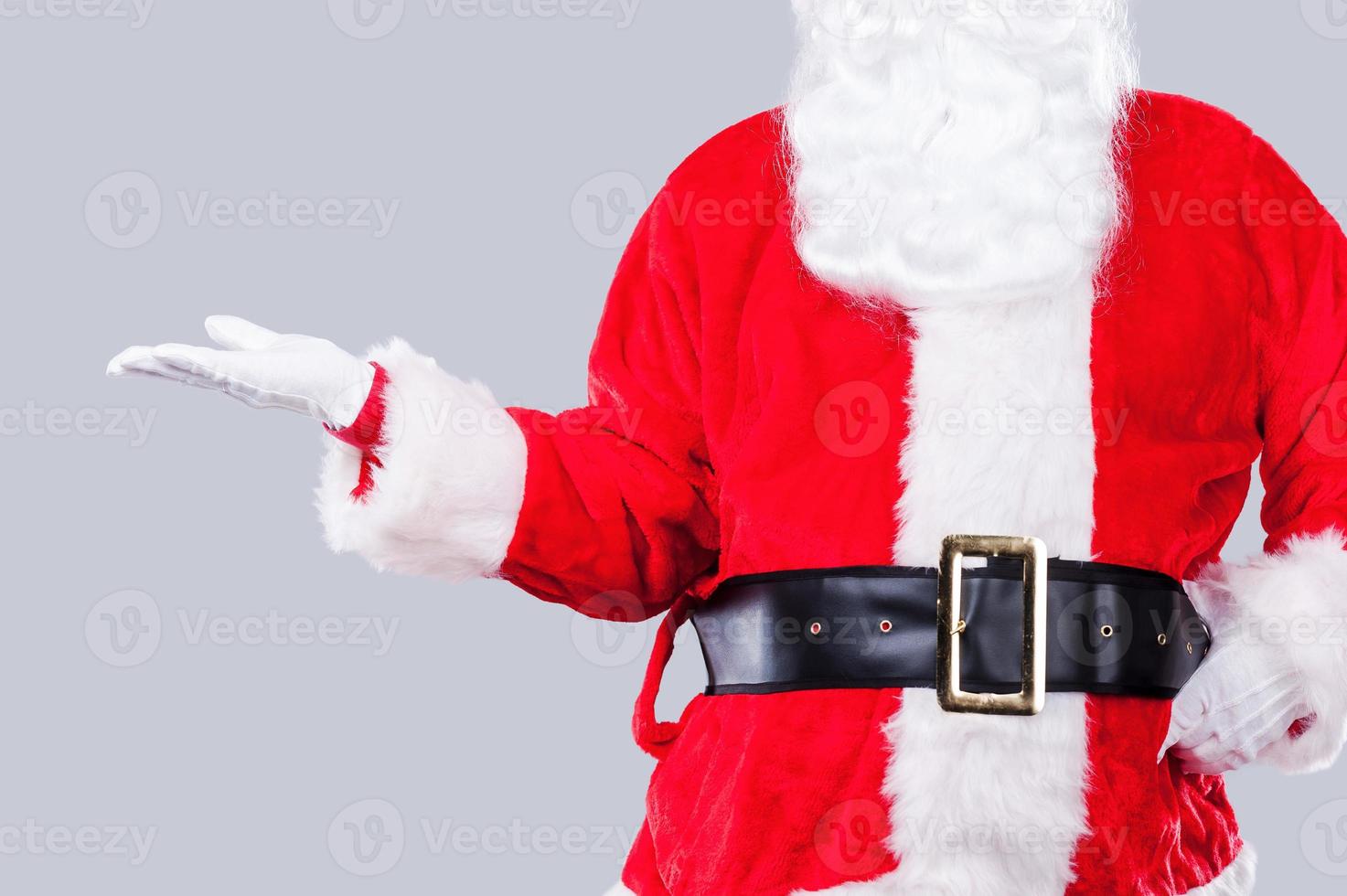 copie el espacio en la mano de santa. santa claus tradicional sosteniendo espacio de copia mientras está de pie contra un fondo gris foto