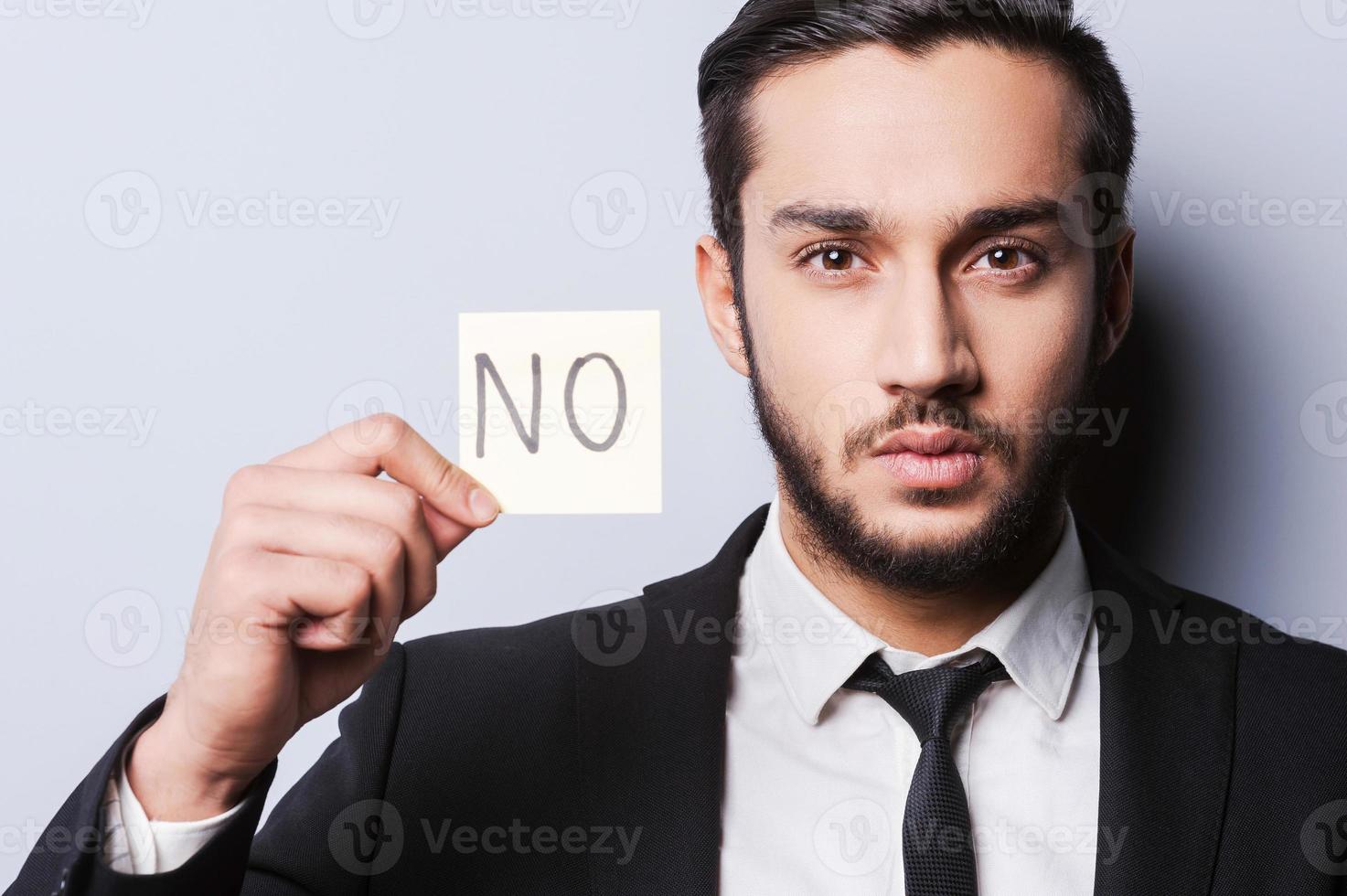 I said No. Handsome young man in formalwear holding adhesive note while standing against grey background photo