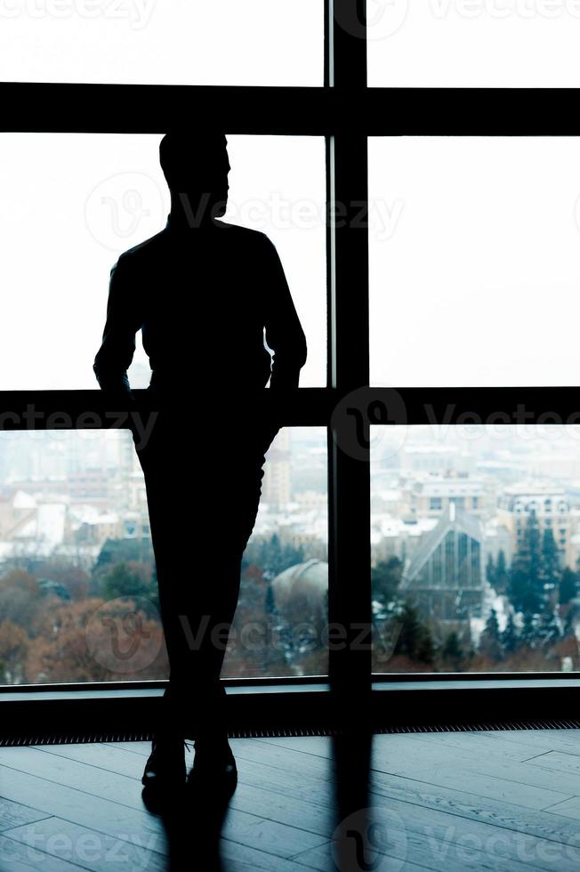 silueta de negocios. silueta de cuerpo entero de un hombre de negocios parado frente a la ventana foto