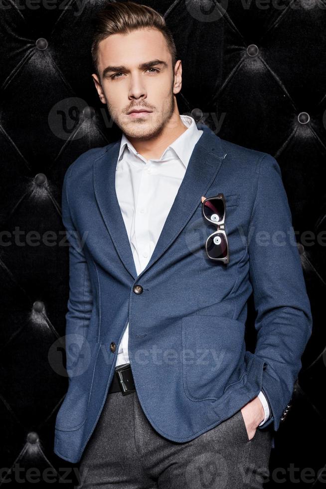 Party boy. Handsome young man in smart casual wear looking at camera while standing against black background photo