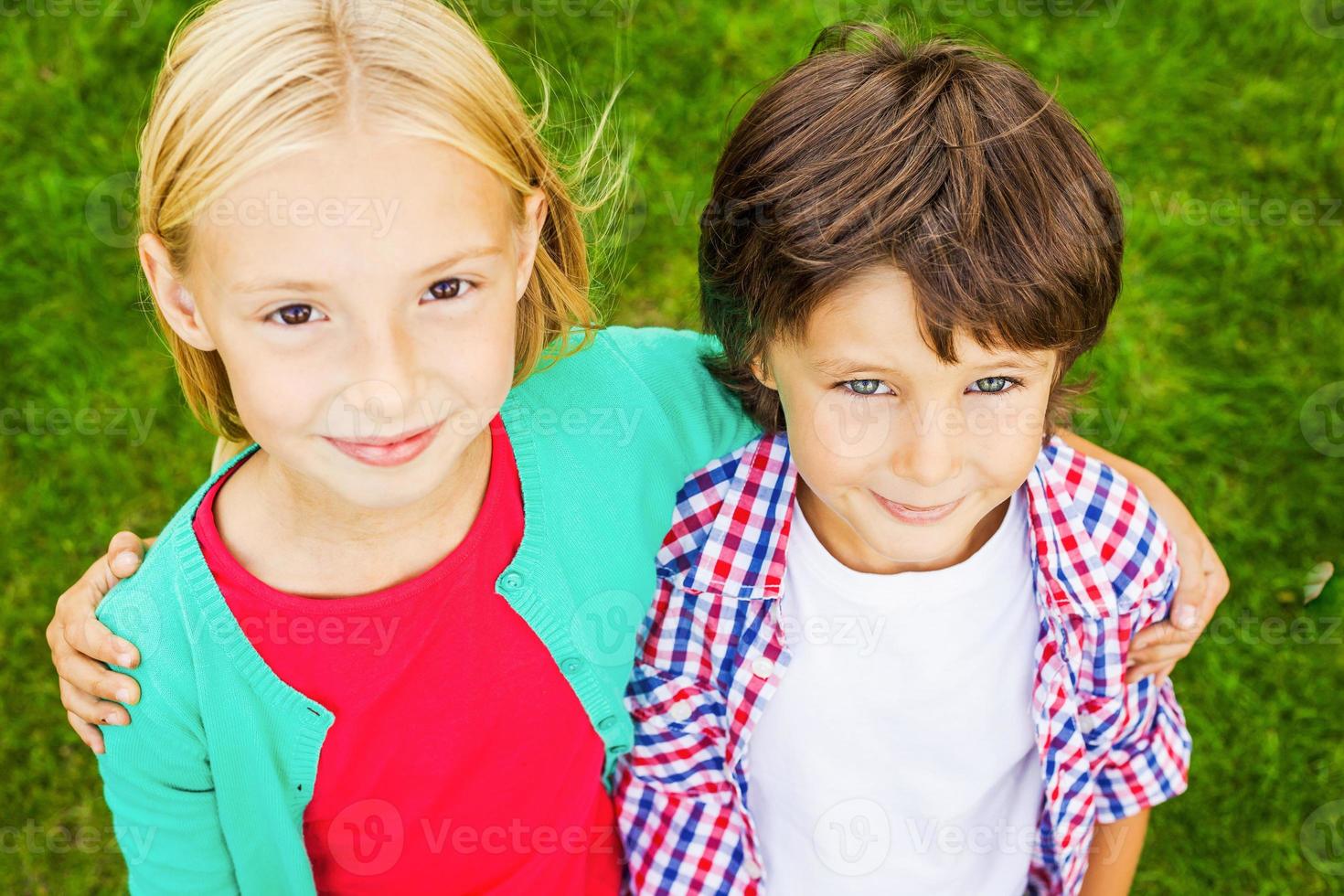 somos la mejor vista de los mejores amigos de dos lindos niños pequeños que se unen y sonríen mientras están juntos en la hierba verde foto