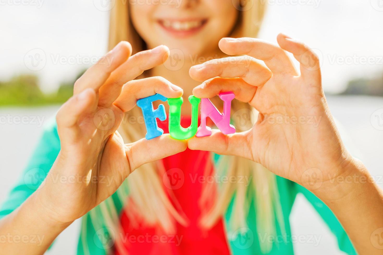 Just for fun Close-up of cheerful little girl holding colorful plastic letters in her hands and smiling while standing outdoors sun photo