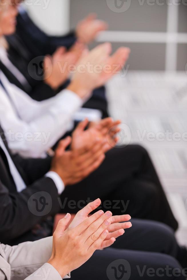 gente aplaudiendo. grupo de empresarios aplaudiendo mientras están sentados en fila foto