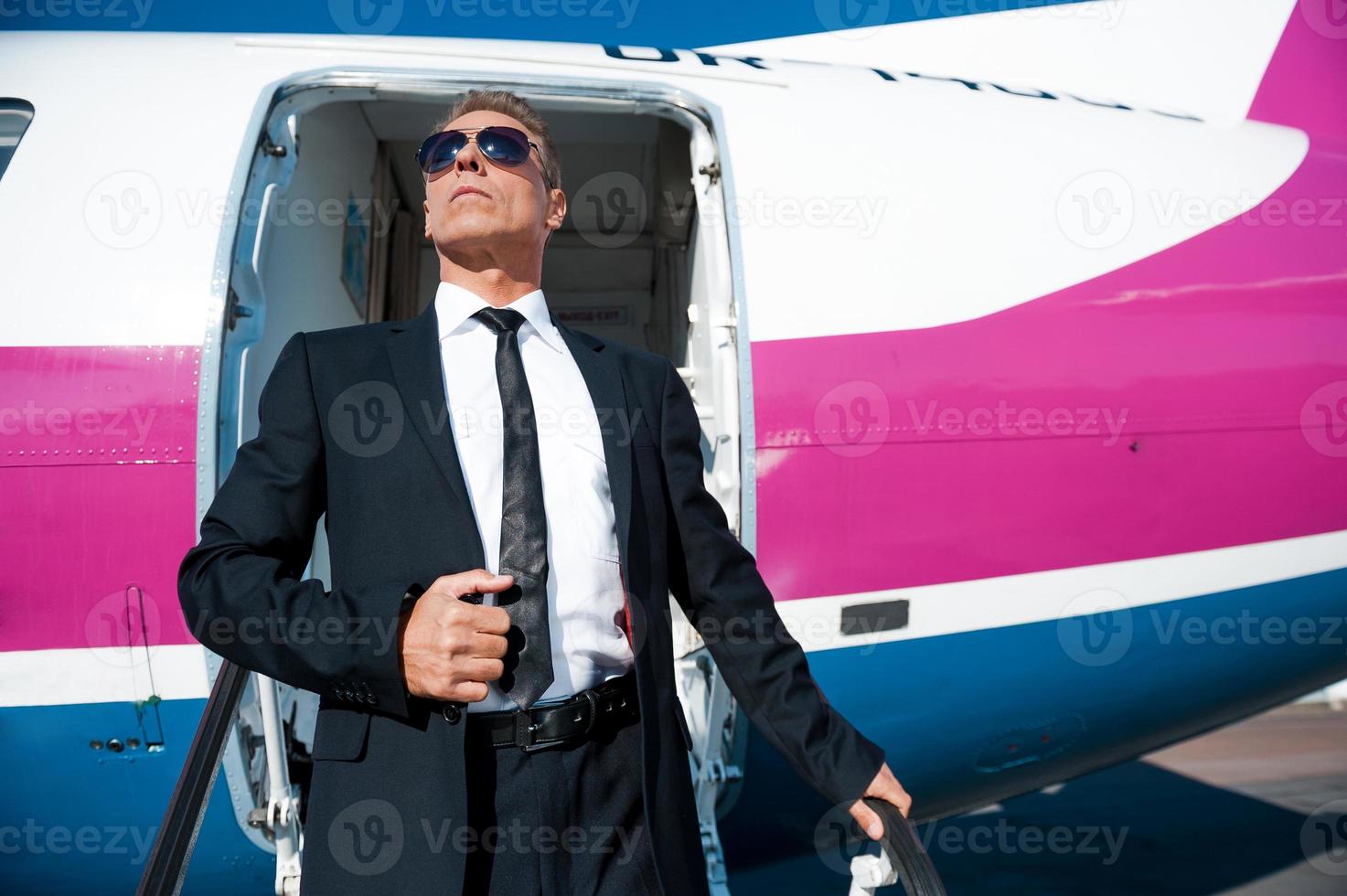 Boss is here. Low angle view of confident mature businessman getting out of airplane and looking away photo