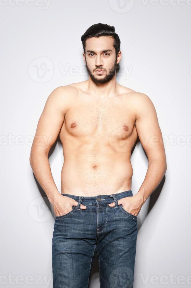 Man with perfect torso. Handsome young muscular man with perfect torso standing against grey background photo