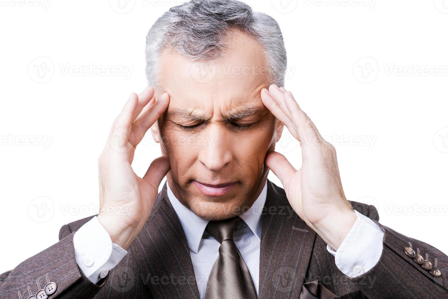 Cannot resist it. Frustrated mature man in formalwear touching head with fingers and keeping eyes closed while standing against white background photo