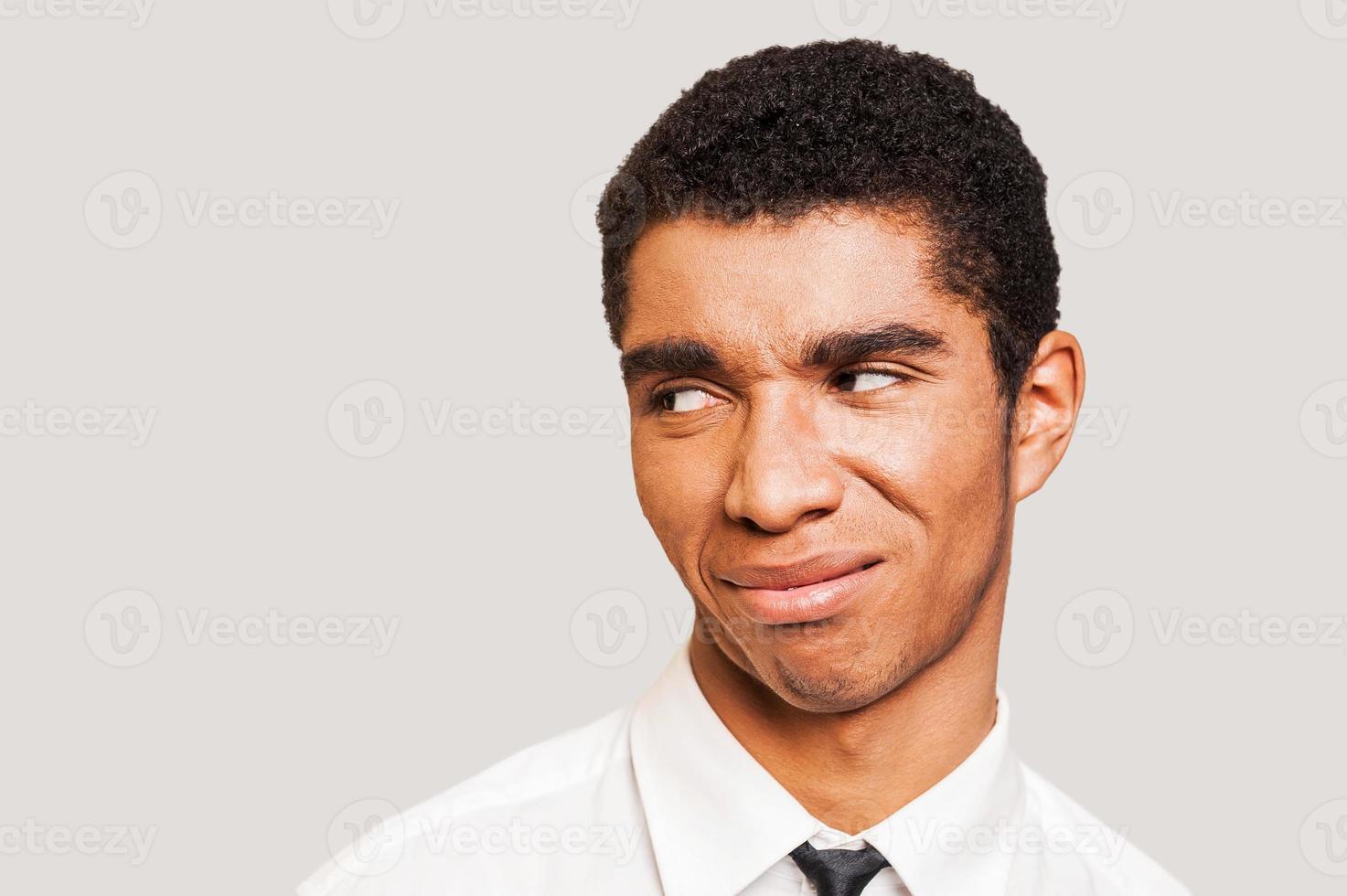 Man in disbelief. Close-up portrait of young Afro-American man showing the disgust on his face while standing against grey background photo