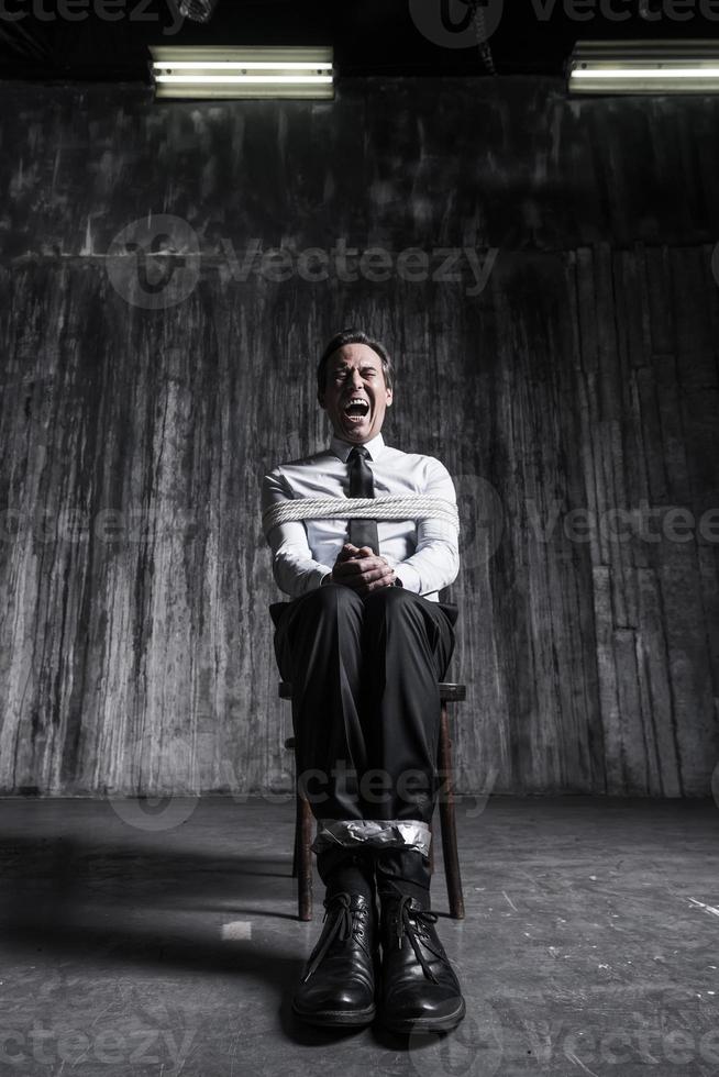 Help me Shocked businessman sitting at the chair and shouting while being tied up photo