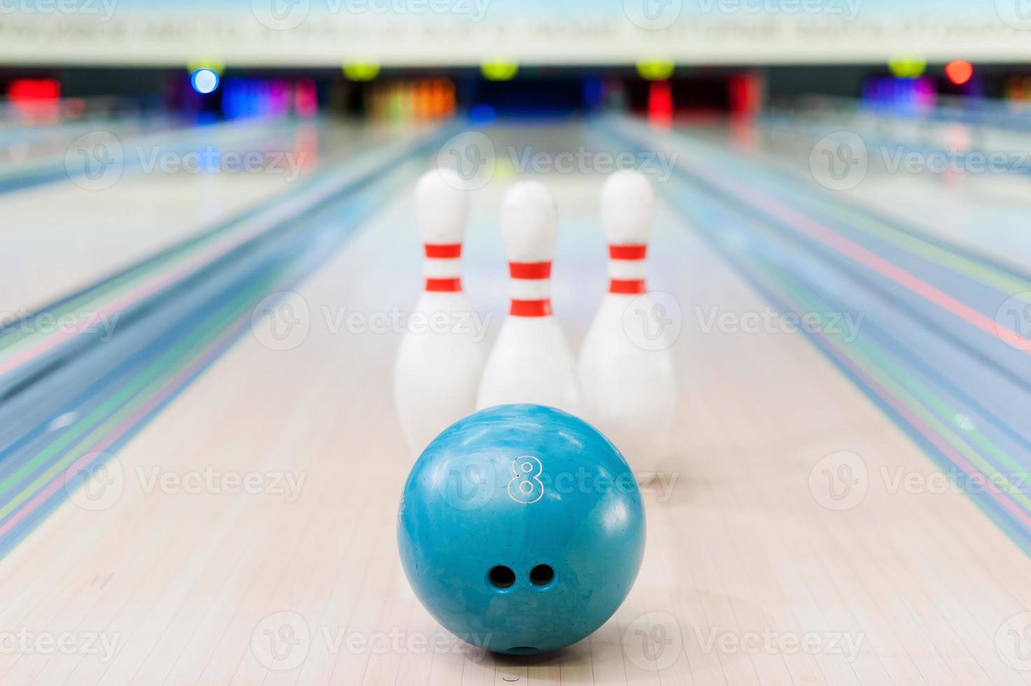 Bowling game. Close-up of blue bowling ball lying against pins staying on bowling alley photo