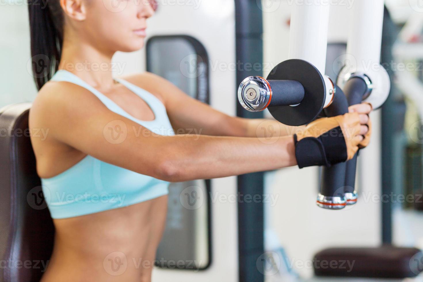 Training in gym. Cropped image of attractive young woman working out in gym photo