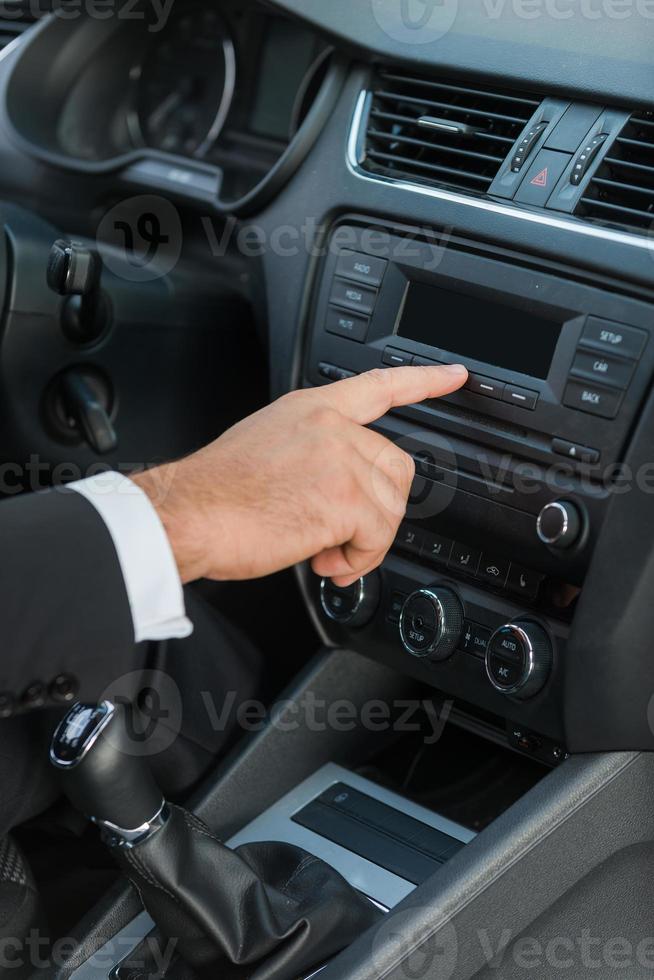 Examining his new car. Close-up of man in formalwear touching dashboard with finger while sitting in car photo